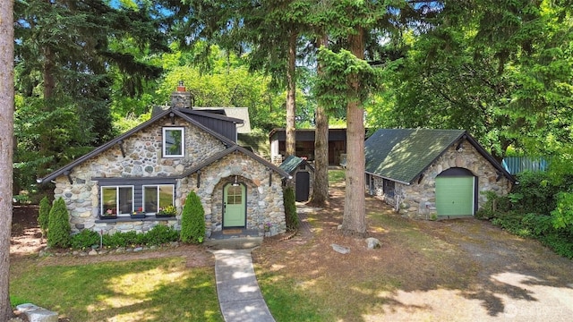 8038 S Ainsworth Ave, Tacoma, WA 98408 - view of front of home with stone siding, an outdoor structure, and a chimney