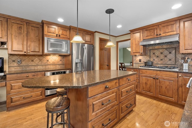 14809 283rd Pl NE, Duvall, WA 98019 - kitchen featuring appliances with stainless steel finishes, under cabinet range hood, light wood finished floors, backsplash, and brown cabinets