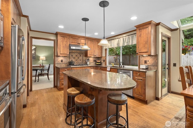 14809 283rd Pl NE, Duvall, WA 98019 - kitchen with appliances with stainless steel finishes, light wood-style floors, a breakfast bar area, a kitchen island, and ornamental molding