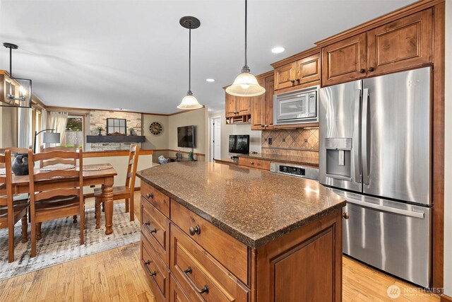 14809 283rd Pl NE, Duvall, WA 98019 - kitchen with stainless steel appliances, brown cabinetry, light wood finished floors, a kitchen island, and decorative backsplash