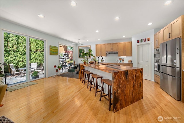 6703 Marshall Ave SE, Auburn, WA 98092 - kitchen with appliances with stainless steel finishes, a kitchen breakfast bar, an island with sink, light wood-style flooring, and recessed lighting