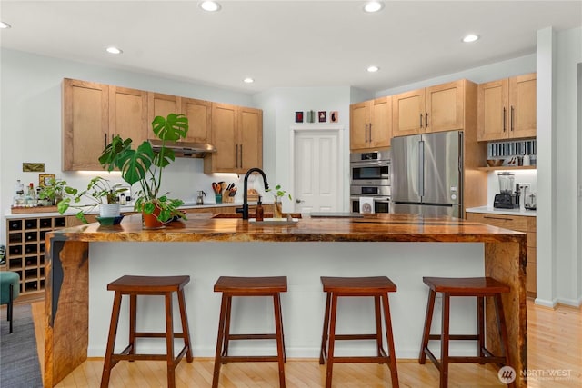 6703 Marshall Ave SE, Auburn, WA 98092 - kitchen featuring appliances with stainless steel finishes, light wood-style floors, a kitchen breakfast bar, recessed lighting, and a kitchen island with sink