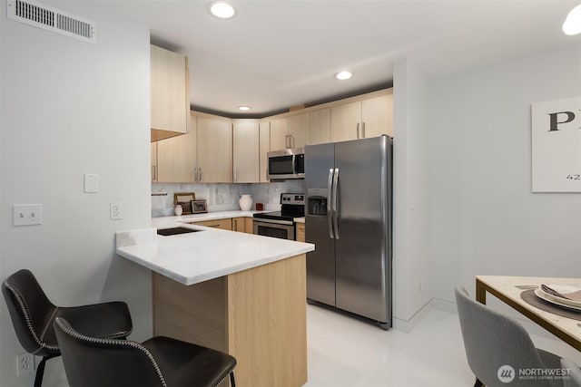 11504 NE 128th Ave Unit 32, Kirkland, WA 98034 - kitchen featuring stainless steel appliances, light brown cabinets, a peninsula, a breakfast bar, and light countertops