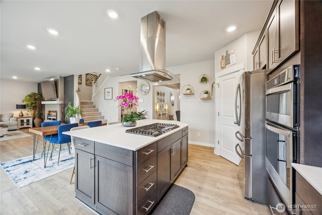 18437 111th Ave E, Puyallup, WA 98374 - kitchen featuring stainless steel appliances, island exhaust hood, light wood-type flooring, a kitchen island, and light countertops