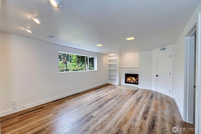 19807 80th Pl W, Edmonds, WA 98026 - unfurnished living room with wood finished floors, a textured ceiling, and a brick fireplace