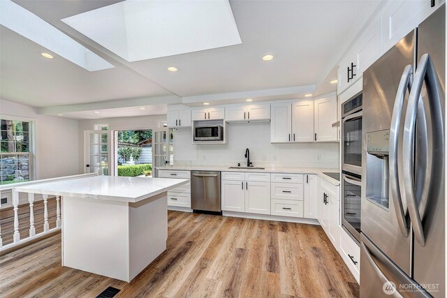 19807 80th Pl W, Edmonds, WA 98026 - kitchen featuring stainless steel appliances, a skylight, recessed lighting, and white cabinetry