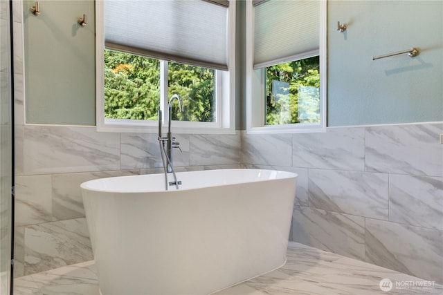 3409 49th St NE, Tacoma, WA 98422 - bathroom featuring tile walls, marble finish floors, a freestanding bath, healthy amount of natural light, and a wainscoted wall