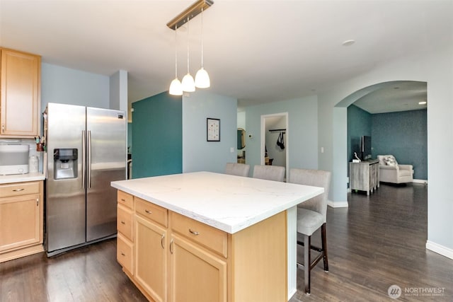 1194 Swan Loop, Dupont, WA 98327 - kitchen with stainless steel refrigerator with ice dispenser, light brown cabinets, a breakfast bar, arched walkways, and dark wood finished floors