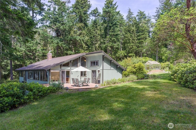 1585 Channel Rd, Lopez Island, WA 98261 - back of house featuring a lawn, a patio, a chimney, a sunroom, and a forest view