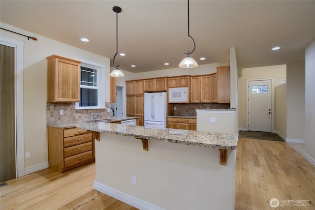 2605 Fir Crest Blvd, Anacortes, WA 98221 - kitchen with white appliances, backsplash, light wood-style flooring, a breakfast bar, and light stone counters