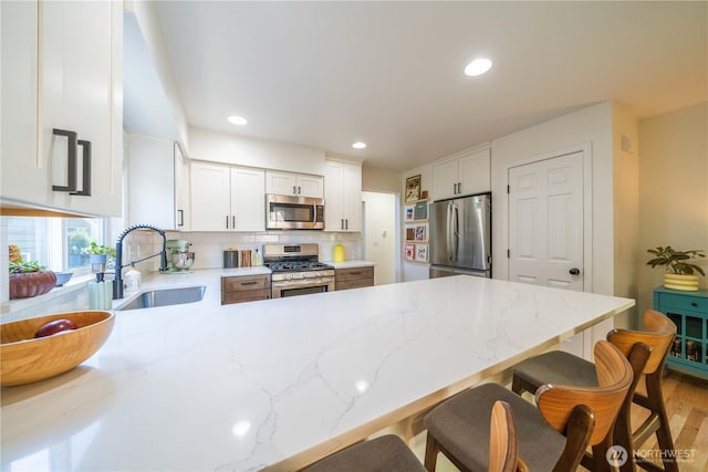 16955 Lookout Mountain Rd SE, Monroe, WA 98272 - kitchen with stainless steel appliances, a peninsula, a kitchen bar, tasteful backsplash, and white cabinetry