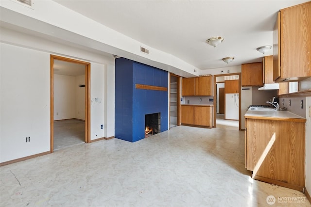 7331 Ridgemont Dr SE, Olympia, WA 98513 - kitchen with brown cabinets, a fireplace, light countertops, light flooring, and under cabinet range hood