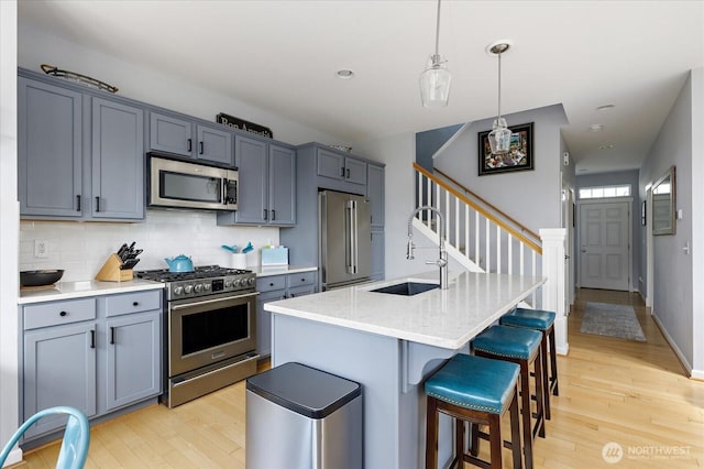 1404 Portside Ct, Freeland, WA 98249 - kitchen featuring stainless steel appliances, light wood-style floors, backsplash, a kitchen bar, and a kitchen island with sink