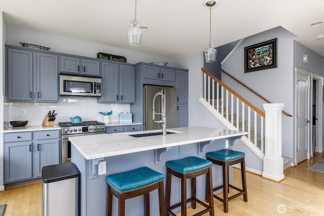 1404 Portside Ct, Freeland, WA 98249 - kitchen featuring stainless steel appliances, light wood-style flooring, tasteful backsplash, a breakfast bar, and decorative light fixtures
