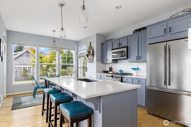 1404 Portside Ct, Freeland, WA 98249 - kitchen featuring high end appliances, light wood-style floors, an island with sink, light stone counters, and decorative backsplash