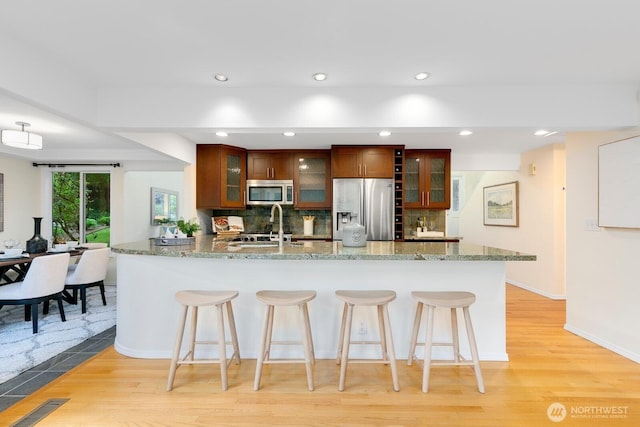 11404 NE 103rd St, Kirkland, WA 98033 - kitchen with appliances with stainless steel finishes, a kitchen breakfast bar, light wood finished floors, backsplash, and recessed lighting