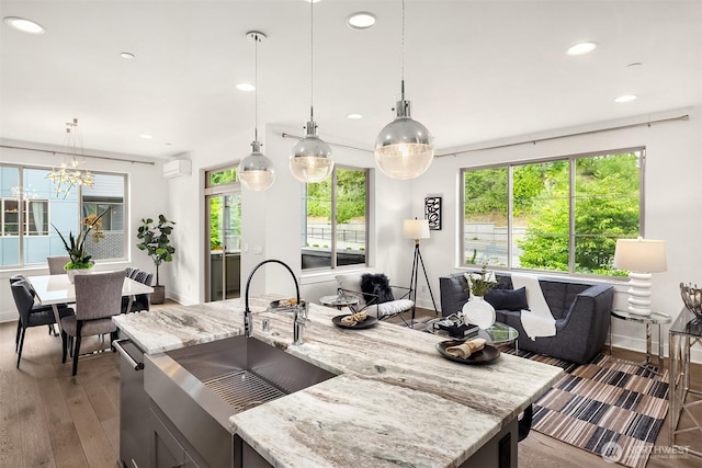11530 117th Ln NE Unit 2, Kirkland, WA 98034 - kitchen with hardwood / wood-style flooring, recessed lighting, light stone countertops, hanging light fixtures, and a wall mounted air conditioner