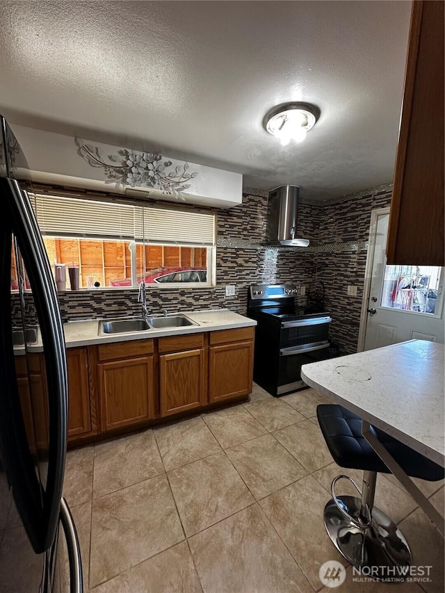 438 Biggs Dr, Moses Lake, WA 98837 - kitchen featuring double oven range, wall chimney exhaust hood, light countertops, brown cabinets, and a textured ceiling