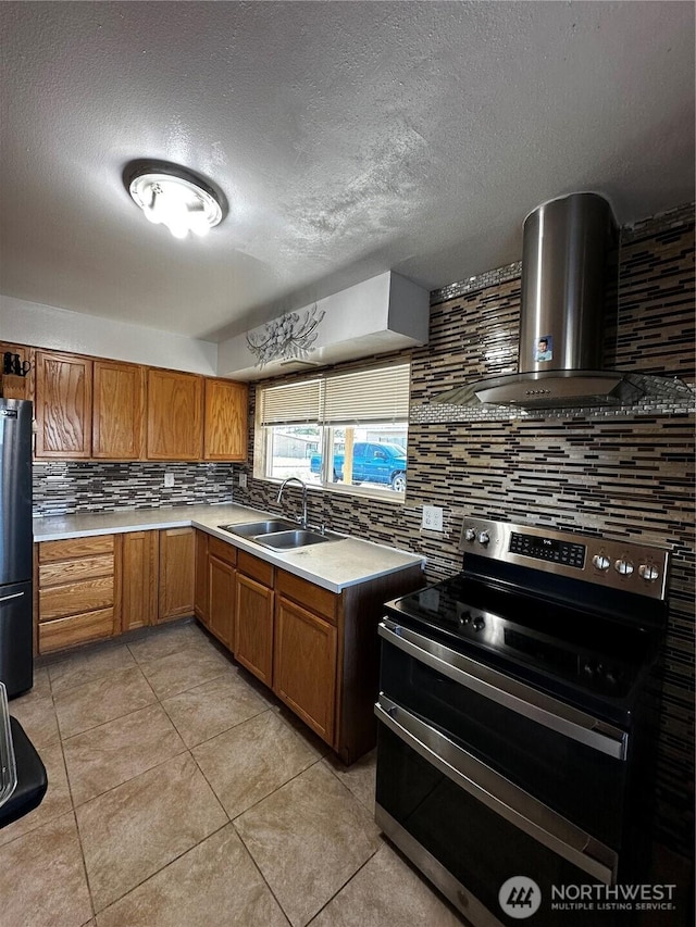 438 Biggs Dr, Moses Lake, WA 98837 - kitchen featuring stainless steel electric range, wall chimney exhaust hood, tasteful backsplash, brown cabinets, and freestanding refrigerator