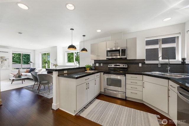 228 24th Ave E Unit A, Seattle, WA 98112 - kitchen with appliances with stainless steel finishes, a peninsula, open floor plan, decorative backsplash, and recessed lighting