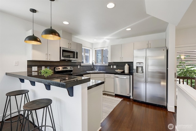 228 24th Ave E Unit A, Seattle, WA 98112 - kitchen with stainless steel appliances, a peninsula, backsplash, recessed lighting, and decorative light fixtures