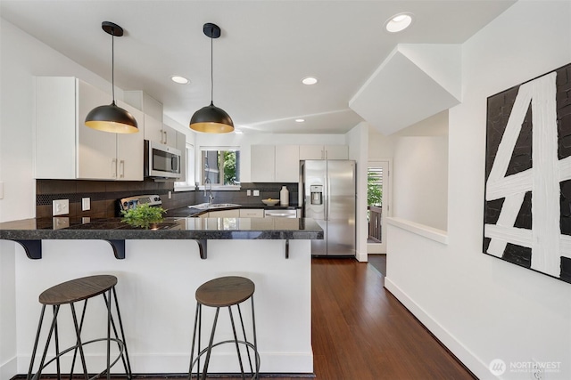 228 24th Ave E Unit A, Seattle, WA 98112 - kitchen with appliances with stainless steel finishes, a peninsula, tasteful backsplash, dark countertops, and decorative light fixtures