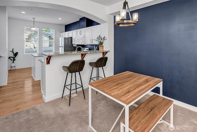 15325 SE 155th Pl Unit Q2, Renton, WA 98058 - kitchen with freestanding refrigerator, white microwave, white cabinetry, arched walkways, and light stone countertops