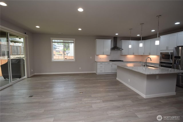 4650 Viridian Ave SW, Port Orchard, WA 98367 - kitchen with wall chimney exhaust hood, appliances with stainless steel finishes, tasteful backsplash, light wood-style floors, and an island with sink