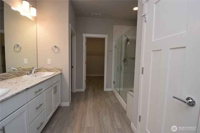 4650 Viridian Ave SW, Port Orchard, WA 98367 - full bathroom featuring double vanity, a shower stall, wood finished floors, and a walk in closet