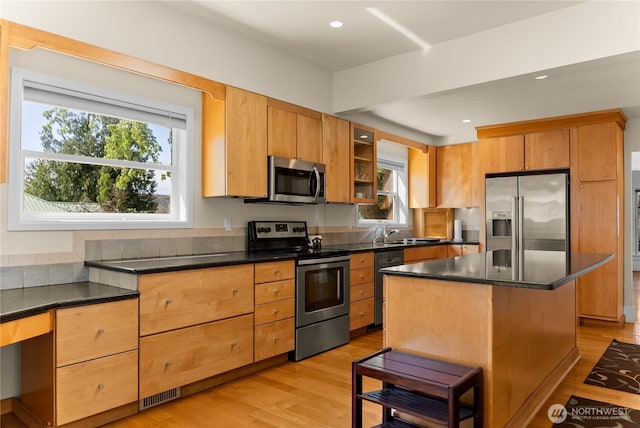 216 4th St E, Tonasket, WA 98855 - kitchen with appliances with stainless steel finishes, dark countertops, light wood-style floors, a breakfast bar, and recessed lighting