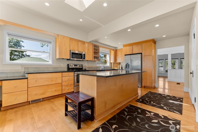 216 4th St E, Tonasket, WA 98855 - kitchen with appliances with stainless steel finishes, a skylight, dark countertops, light wood-style floors, and recessed lighting
