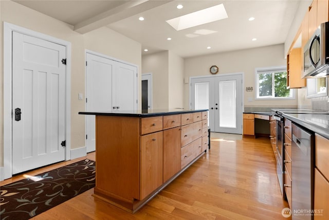 216 4th St E, Tonasket, WA 98855 - kitchen featuring a skylight, appliances with stainless steel finishes, light wood-type flooring, a center island, and dark countertops