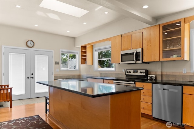 216 4th St E, Tonasket, WA 98855 - kitchen featuring appliances with stainless steel finishes, a kitchen breakfast bar, dark countertops, a skylight, and french doors
