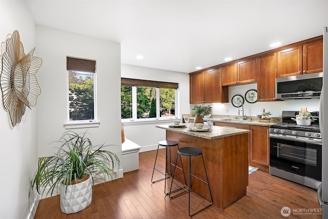 5955 Delridge Way SW, Seattle, WA 98106 - kitchen with stainless steel appliances, a kitchen island, a breakfast bar area, brown cabinets, and recessed lighting