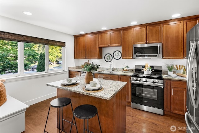 5955 Delridge Way SW, Seattle, WA 98106 - kitchen featuring stainless steel appliances, a breakfast bar area, light stone counters, dark wood-style floors, and recessed lighting