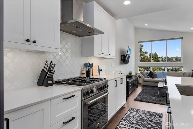 3418 23rd Ave W, Seattle, WA 98199 - kitchen featuring wall chimney range hood, stainless steel stove, lofted ceiling, dark wood-type flooring, and backsplash