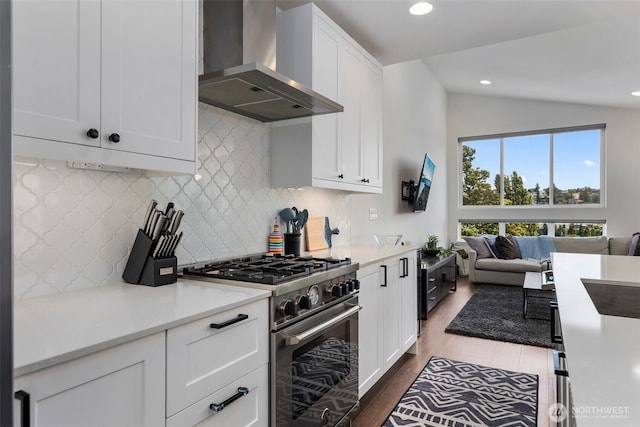 3418 23rd Ave W, Seattle, WA 98199 - kitchen featuring wall chimney range hood, stainless steel stove, vaulted ceiling, dark wood finished floors, and decorative backsplash