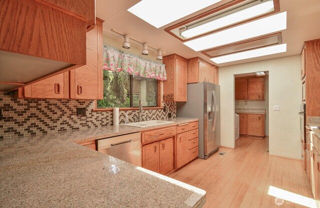 1203 Contra Costa Ave, Fircrest, WA 98466 - kitchen with appliances with stainless steel finishes, light wood finished floors, decorative backsplash, washing machine and dryer, and track lighting