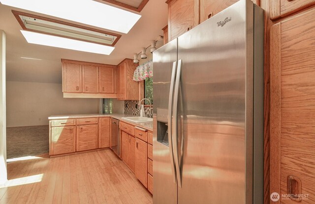 1203 Contra Costa Ave, Fircrest, WA 98466 - kitchen featuring appliances with stainless steel finishes, a skylight, light wood finished floors, light countertops, and light brown cabinetry