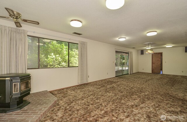 1203 Contra Costa Ave, Fircrest, WA 98466 - carpeted empty room featuring plenty of natural light, a wood stove, and ceiling fan