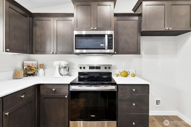 281 Shallow Shore Rd, Bellingham, WA 98229 - kitchen featuring appliances with stainless steel finishes, dark brown cabinets, light countertops, wood finished floors, and vaulted ceiling