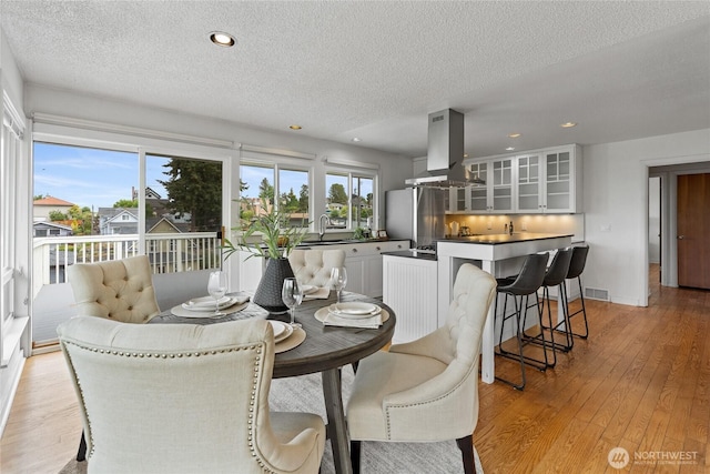 4815 N Huson St, Tacoma, WA 98407 - dining room featuring a textured ceiling, light wood-style floors, recessed lighting, and bar with sink