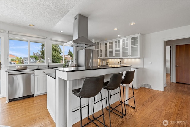 4815 N Huson St, Tacoma, WA 98407 - kitchen featuring stainless steel appliances, island exhaust hood, a kitchen island, light wood-style flooring, and recessed lighting