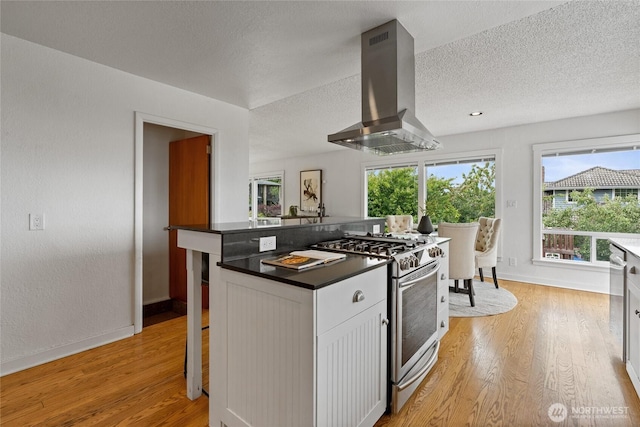 4815 N Huson St, Tacoma, WA 98407 - kitchen featuring stainless steel range with gas cooktop, island range hood, dark countertops, light wood-style flooring, and a textured ceiling