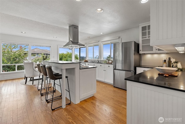 4815 N Huson St, Tacoma, WA 98407 - kitchen featuring island range hood, freestanding refrigerator, light wood-style flooring, a textured ceiling, and a breakfast bar area