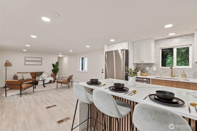 15409 Westshore Dr SE, Yelm, WA 98597 - kitchen featuring stainless steel appliances, a breakfast bar area, white cabinets, recessed lighting, and light stone countertops