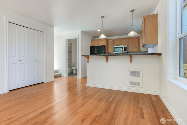 1426A NW 59th St, Seattle, WA 98107 - kitchen featuring stainless steel microwave, freestanding refrigerator, a kitchen bar, light wood-style floors, and decorative light fixtures