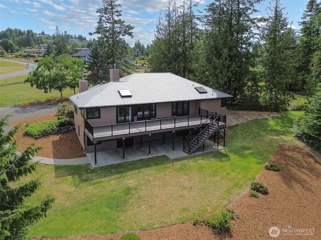 412 Doe Run Rd, Sequim, WA 98382 - rear view of house featuring a wooden deck, stairs, a lawn, a chimney, and a patio