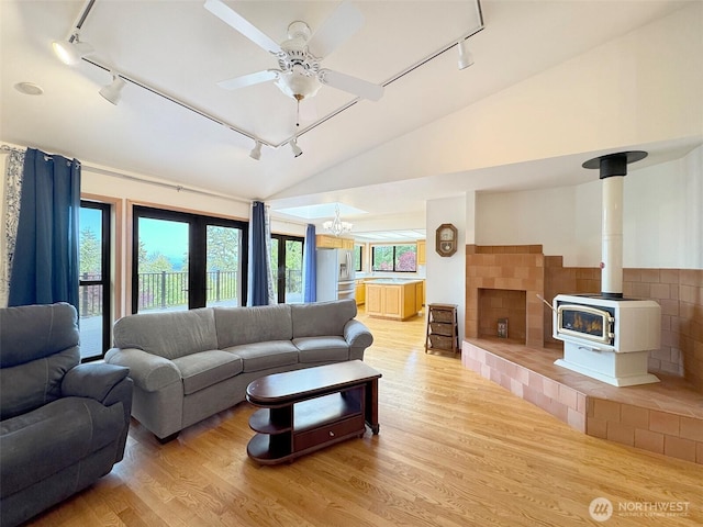 412 Doe Run Rd, Sequim, WA 98382 - living area with rail lighting, light wood-style floors, vaulted ceiling, a wood stove, and ceiling fan