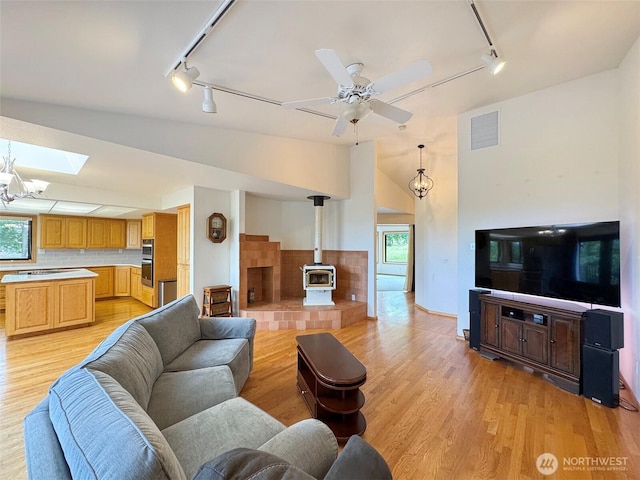 412 Doe Run Rd, Sequim, WA 98382 - living room with track lighting, a wood stove, light wood-style floors, lofted ceiling, and a ceiling fan